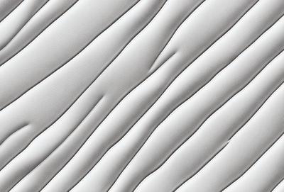 The primary subject of the image is a white wall with a pattern of wrinkles and folds. The setting is a room with a white background. The visual style is a close-up of the wall, showcasing the intricate details of the wrinkles. The colors and mood of the image are predominantly white, giving it a clean and minimalist appearance.