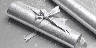 The primary subject of the image is a white bow, which is tied around a package. The setting is a white background, and the visual style is a photo. The colors and mood of the image are predominantly white, giving it a clean and elegant appearance.