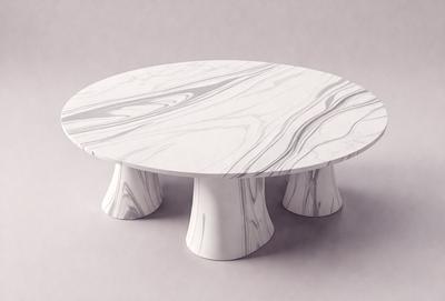 The primary subject of the image is a white marble table with a round shape. The table is placed on a grey surface, which serves as the setting or background. The visual style of the image is a photo, capturing the details of the marble table and its surroundings. The colors and mood of the image are predominantly neutral, with the white marble table and grey surface creating a clean and elegant atmosphere.