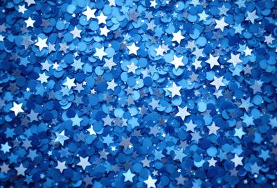The primary subject of the image is a blue star-filled background. The setting is a blue sky with a pattern of stars scattered throughout the scene. The visual style is a close-up of the blue star-filled background, creating a sense of depth and detail. The colors and mood of the image are predominantly blue, with the stars adding a touch of white and sparkling effect.