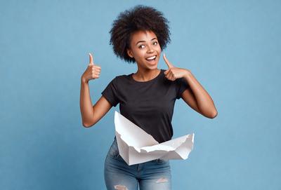 The primary subject of the image is a woman with a big smile, giving a thumbs up. She is wearing a black shirt and holding a piece of paper. The setting is a blue background, and the visual style appears to be a photo. The woman's smile and thumbs up convey a positive and cheerful mood.