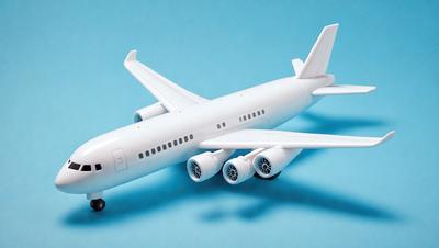 The primary subject of the image is a white model airplane. The airplane is placed on a blue surface, which serves as the background. The visual style of the image is a photo, capturing the details of the model airplane. The colors and mood of the image are predominantly blue and white, creating a sense of calm and precision.