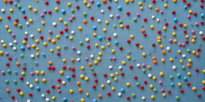 The primary subject of the image is a blue surface with a pattern of colorful balls, including red, blue, yellow, and green. The setting appears to be a room with a blue tablecloth, and the visual style is a close-up of the pattern. The colors and mood of the image are vibrant and lively, with the balls creating a playful and cheerful atmosphere.