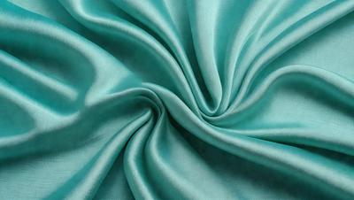 The primary subject of the image is a blue fabric, which appears to be a piece of silk. The setting is a close-up of the fabric, showcasing its texture and color. The visual style is a detailed, up-close view of the fabric, emphasizing its intricate patterns and texture. The colors and mood of the image are predominantly blue, creating a calm and serene atmosphere.