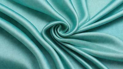 The primary subject of the image is a blue fabric, which is the main object, scene, or focus of the image. The setting is a blue background, and the visual style is a photo. The dominant colors are blue and green, creating a calm and soothing atmosphere.
