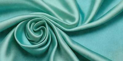 The primary subject of the image is a close-up of a piece of green fabric, possibly a piece of silk. The setting is a blue background, which creates a striking contrast with the green fabric. The visual style appears to be a close-up of the fabric, showcasing its texture and details. The colors and mood of the image are predominantly green and blue, giving it a calm and serene atmosphere.