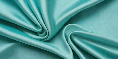The primary subject of the image is a piece of green fabric, which is the main object, scene, or focus of the image. The setting or background of the image is a blue surface, which adds to the overall atmosphere. The visual style of the image is a close-up of the green fabric, showcasing its texture and details. The colors and mood of the image are predominantly green and blue, creating a calm and serene atmosphere.