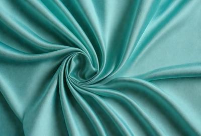 The primary subject of the image is a blue fabric, which appears to be a piece of cloth or a curtain. The setting is a blue background, which complements the blue fabric. The visual style is a close-up of the fabric, showcasing its texture and pattern. The colors and mood of the image are predominantly blue, creating a calm and serene atmosphere.