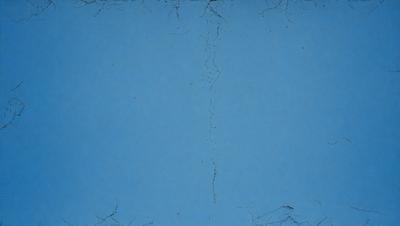 The primary subject of the image is a blue background with a cracked or peeling surface. The setting is a blue sky, and the visual style appears to be a photo. The colors and mood of the image are predominantly blue, creating a calm and serene atmosphere.