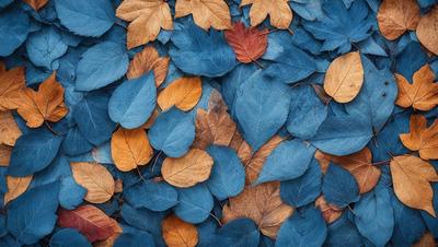 The primary subject of the image is a pile of leaves, predominantly yellow and blue, scattered across a blue surface. The leaves are arranged in various shapes and sizes, creating a visually appealing and natural scene. The setting appears to be outdoors, possibly in a park or garden, where the leaves have fallen from trees. The visual style of the image is a close-up of the leaves, emphasizing their colors and textures. The overall atmosphere of the image is serene and peaceful, with the blue background