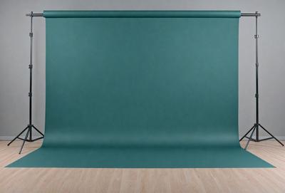 The primary subject of the image is a large green curtain. The curtain is hanging on a wall, covering a significant portion of the wall's surface. The setting is indoors, with the curtain serving as a backdrop for the scene. The visual style of the image is a photo, capturing the curtain's texture and color. The dominant colors in the image are green, creating a calm and soothing atmosphere.