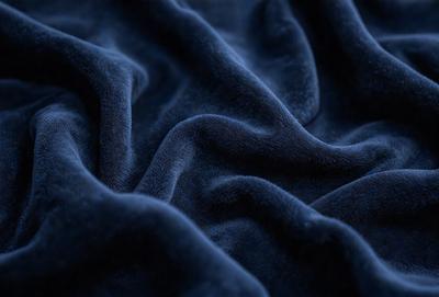 The primary subject of the image is a blue fabric, which appears to be a piece of cloth or a blanket. The setting is a dark room, and the visual style is a close-up of the fabric. The colors and mood of the image are predominantly dark and moody, with the blue fabric being the main focus.