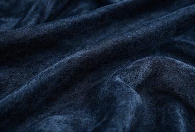 The primary subject of the image is a blue fabric, which is the main object, scene, or focus of the image. The setting or background is a dark blue cloth, and the visual style is a photo. The colors and mood of the image are predominantly dark blue, creating a moody and dramatic atmosphere.