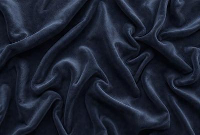 The primary subject of the image is a blue fabric, which appears to be a piece of cloth or a curtain. The setting is a dark room, and the visual style is a close-up of the fabric. The colors and mood of the image are predominantly dark and moody, with the blue fabric being the main focus.