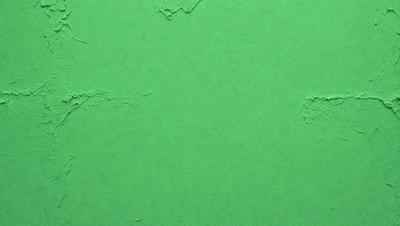 The image features a green wall with a few small holes in it. The wall appears to be made of cement or a similar material. The green color of the wall creates a calm and soothing atmosphere. The holes in the wall add a touch of texture and interest to the otherwise plain surface.