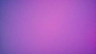 The primary subject of the image is a large, pink wall. The setting is a room with a purple background. The visual style is a close-up of the wall, which gives a sense of depth and texture. The colors and mood of the image are predominantly purple, creating a calm and serene atmosphere.