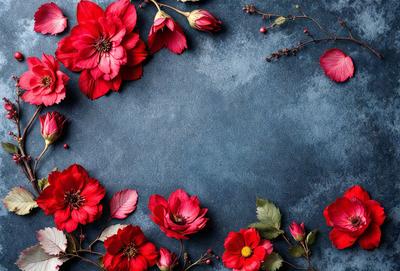 The primary subject of the image is a bouquet of red flowers, which are the main focus of the scene. The flowers are arranged in a visually appealing manner, creating a sense of beauty and elegance. The setting is a blue surface, which serves as a striking contrast to the red flowers. The visual style of the image is a close-up of the flowers, allowing the viewer to appreciate the details and textures of the petals. The colors and mood of the image are predominantly red, which evokes
