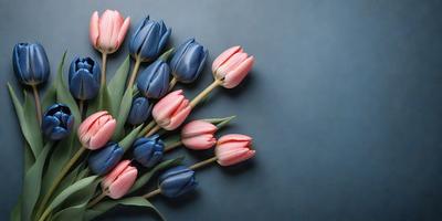 The primary subject of the image is a bouquet of pink and blue tulips. The setting is a blue background, which creates a contrasting and visually appealing scene. The visual style is a close-up of the flowers, showcasing their vibrant colors and details. The overall atmosphere is one of freshness and beauty, as the flowers are the main focus of the image.