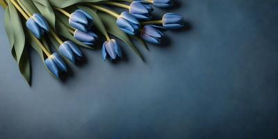 The primary subject of the image is a bouquet of blue flowers, which are the main focus of the scene. The flowers are arranged in a vase and are placed on a blue surface, which adds a contrasting element to the composition. The visual style of the image is a close-up of the flowers, showcasing their details and beauty. The colors and mood of the image are predominantly blue, creating a calm and serene atmosphere.