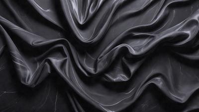 The primary subject of the image is a close-up of a black fabric, possibly a piece of clothing or a curtain. The setting is a dark room, and the visual style appears to be a photo. The colors in the image are predominantly black, creating a moody and dramatic atmosphere.