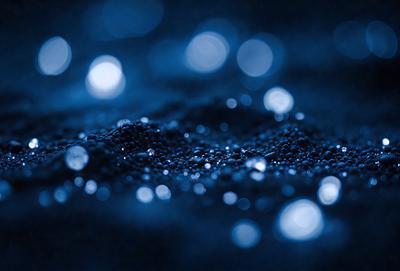 The primary subject of the image is a close-up of a blue background with a pattern of tiny lights. The setting appears to be a dark room, and the visual style is a combination of a photo and digital art. The dominant colors are blue and black, creating a moody and atmospheric scene.