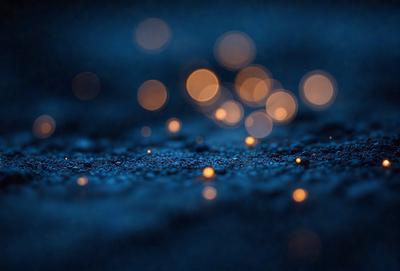 The primary subject of the image is a close-up of a black surface with a pattern of yellow lights. The setting appears to be a dark room, and the visual style is a combination of a photo and digital art. The dominant colors are black and yellow, creating a moody and dramatic atmosphere.