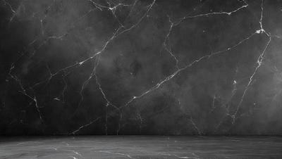 The primary subject of the image is a marble wall with a black background. The setting is a room with a black wall, and the visual style is a photo. The colors and mood of the image are dark and moody, with the marble wall and black background creating a dramatic and sophisticated atmosphere.