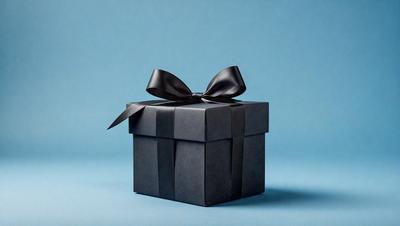 The primary subject of the image is a black box with a black bow on top. The box is placed on a blue surface, which serves as the setting or background. The visual style of the image is a photo, capturing the details of the box and bow. The colors in the image are predominantly black and blue, creating a sense of elegance and sophistication.