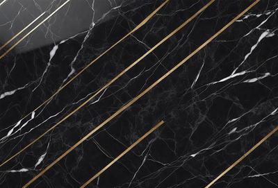 The primary subject of the image is a black marble countertop with gold stripes. The setting is a kitchen, and the visual style is a close-up of the marble countertop. The dominant colors are black and gold, creating a luxurious and elegant atmosphere.