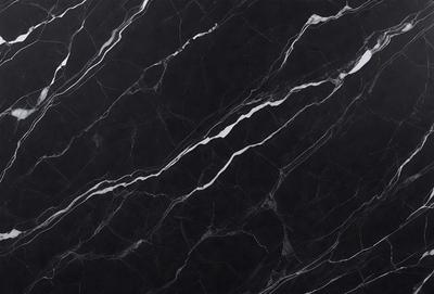 The primary subject of the image is a black marble countertop. The setting is a kitchen, with the countertop being the main focus of the scene. The visual style is a close-up of the marble countertop, showcasing its texture and pattern. The colors and mood of the image are predominantly dark, with the black marble countertop being the main source of contrast.