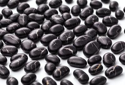 The primary subject of the image is a collection of black rocks, which are the main objects in the scene. The setting is a white surface, possibly a table or a countertop, where the rocks are placed. The visual style of the image is a close-up of the rocks, showcasing their details and textures. The dominant colors in the image are black and white, giving the scene a simple and minimalist appearance.