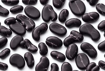 The primary subject of the image is a collection of black and white heart-shaped rocks. These rocks are arranged in a pattern, creating a visually appealing display. The setting is a white background, which provides a clean and minimalist look to the scene. The visual style of the image is a combination of photo and digital art, as the heart-shaped rocks are carefully arranged and the overall composition is well-executed. The colors and mood of the image are predominantly black and white, giving it a classic and