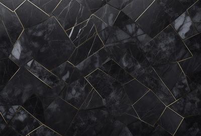 The primary subject of the image is a black and gold marble tile. The setting is a black and gold marble wall, which serves as the background. The visual style is a close-up of the marble tile, showcasing its intricate design. The colors and mood of the image are predominantly black and gold, giving it a luxurious and elegant appearance.
