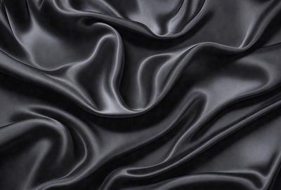 The primary subject of the image is a close-up of a black fabric, possibly a piece of clothing or a curtain. The setting is a dark background, which emphasizes the fabric's texture and pattern. The visual style appears to be a photo, as it captures the details of the fabric. The colors and mood of the image are predominantly dark, with the black fabric being the main focus.
