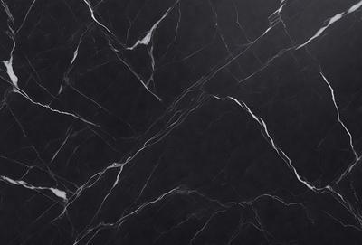 The primary subject of the image is a black marble countertop. The setting is a kitchen, with the countertop being the main focus of the scene. The visual style is a close-up of the marble countertop, showcasing its texture and pattern. The colors and mood of the image are predominantly dark, with the black marble countertop being the main source of contrast.