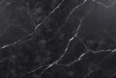The primary subject of the image is a black marble countertop. The setting is a kitchen, with the countertop being the main focus of the scene. The visual style is a close-up of the marble countertop, showcasing its texture and pattern. The colors and mood of the image are predominantly dark, with the black marble countertop being the main source of contrast.