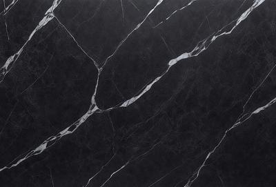 The primary subject of the image is a black marble countertop. The setting is a kitchen, with the countertop being the main focus of the scene. The visual style is a close-up of the marble countertop, showcasing its texture and pattern. The colors and mood of the image are predominantly dark, with the black marble countertop being the main source of contrast.