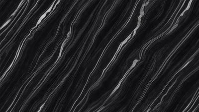 The primary subject of the image is a black and white patterned surface, which appears to be a marble or stone texture. The setting is a dark background, which contrasts with the patterned surface. The visual style is a close-up of the pattern, showcasing the intricate details of the design. The colors and mood of the image are predominantly dark, with the black and white pattern creating a sense of depth and contrast.