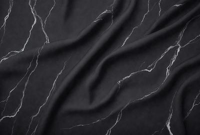 The primary subject of the image is a black fabric, possibly a piece of clothing or a curtain. The setting is a black and white marble surface, which serves as the background. The visual style is a close-up of the fabric, showcasing its texture and details. The colors and mood of the image are predominantly black and white, giving it a classic and elegant appearance.
