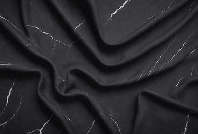 The primary subject of the image is a black fabric, possibly a piece of marble fabric, with a pattern of white veins. The setting is a black background, which contrasts with the fabric. The visual style is a close-up of the fabric, showcasing its texture and pattern. The colors and mood of the image are dark and dramatic, with the black fabric and white veins creating a striking contrast.