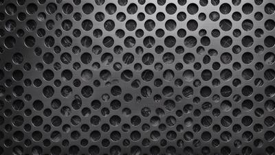 The primary subject of the image is a pattern of holes on a black surface. The setting is a dark background, and the visual style appears to be a close-up of the pattern. The dominant colors are black and silver, creating a moody atmosphere.