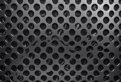 The primary subject of the image is a close-up of a metal surface with a pattern of holes. The setting is a black background, and the visual style appears to be a photo. The dominant colors are black and silver, creating a sleek and modern atmosphere.
