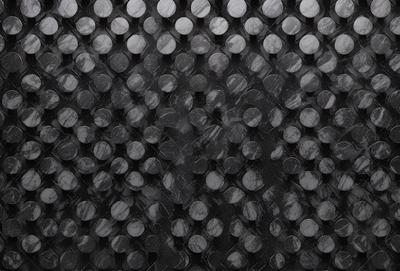 The primary subject of the image is a pattern of circles, which are arranged in a black and white checkered pattern. The setting is a black background, and the visual style appears to be a combination of a photo and a digital art or illustration. The dominant colors are black and white, creating a classic and timeless atmosphere.