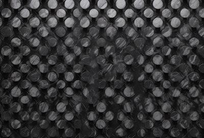 The primary subject of the image is a pattern of circles, which are arranged in a black and white checkered pattern. The setting is a black background, and the visual style appears to be a combination of a photo and a digital art or illustration. The dominant colors are black and white, creating a classic and timeless atmosphere.