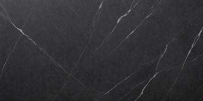 The primary subject of the image is a close-up of a marble countertop. The setting is a kitchen, with the countertop being the main focus of the scene. The visual style is a photo, capturing the natural texture and beauty of the marble surface. The colors and mood of the image are predominantly dark, with the marble countertop being the main source of light and contrast.