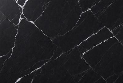 The primary subject of the image is a black marble countertop. The setting is a kitchen, with the countertop being the main focus of the scene. The visual style is a close-up of the marble countertop, showcasing its texture and pattern. The colors and mood of the image are predominantly dark, with the black marble countertop being the main source of contrast.