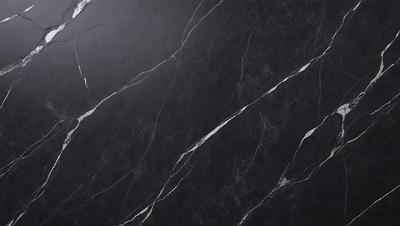 The primary subject of the image is a black marble countertop. The setting is a kitchen, with the countertop being the main focus of the scene. The visual style is a close-up of the marble countertop, showcasing its texture and pattern. The colors and mood of the image are predominantly dark, with the black marble countertop being the main source of contrast.