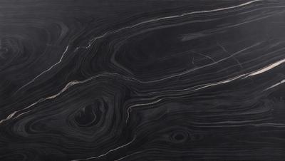 The image features a black marble countertop with a unique, swirling pattern. The countertop appears to be a part of a kitchen or bathroom setting. The visual style of the image is a close-up of the marble countertop, showcasing its intricate design. The colors and mood of the image are predominantly dark, with the black marble providing a striking contrast against the surrounding environment.