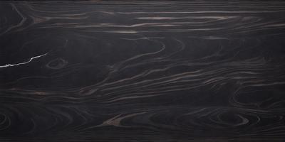 The primary subject of the image is a wooden table with a black surface. The table appears to be made of wood and has a unique pattern on its surface. The setting is indoors, with the table being the main focus of the image. The visual style is a close-up of the wooden table, showcasing its texture and pattern. The colors in the image are predominantly black, giving the table a sleek and modern appearance.