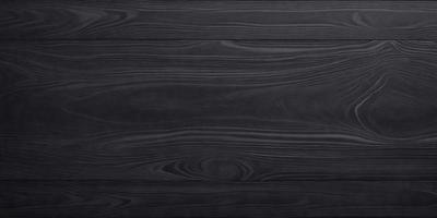 The primary subject of the image is a wooden surface, possibly a table or a countertop. The setting is a room with a black wooden floor, and the visual style appears to be a photo of the wooden surface. The colors and mood of the image are predominantly black, giving it a dark and moody atmosphere.